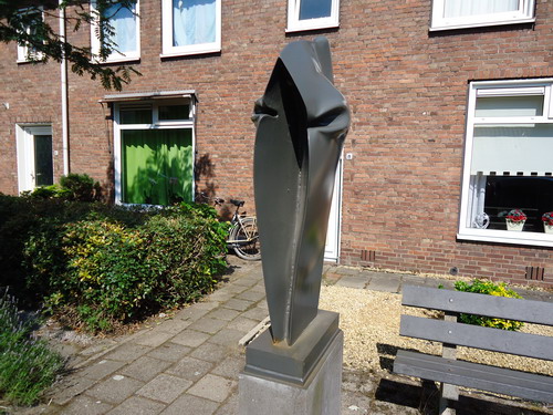 Berghuisstraat
De vrije geest van Nico Betjes waart ook door de Berghuisstraat. Dit beeld werd namelijk door de gemeente ‘aangekocht’ in het jaar 1979.
Dat betekent dat Betjes dit werk niet in opdracht heeft gemaakt, maar volledig zijn eigen gang kon gaan. En dat deed hij het liefst. Hakkenb , schuren, vijlen, Betjes was uren bezig met blokken hout om er geschikte mallen voor zijn kunstwerken van te maken. Deze houtblokken perste hij met zijn eigen hogedrukpers in stalen platen. Zo verkreeg hij de voor hem zo kenmerkende bijzondere vorm. Betjes beelden zien er over het algemeen massief uit. Toch zijn de meeste beelden hol. Opgebouwd uit metalen platen van slechts enkele millimeters dik. Klop er maar eens op.

Bron: Blik op Beeld, Tekstbureau Zonneveld & Thöne i.o.v. gemeente Beverwijk, 2006.
Foto en bewerking: Co Backer

Keywords: bwijk Openbare Kunstwerken