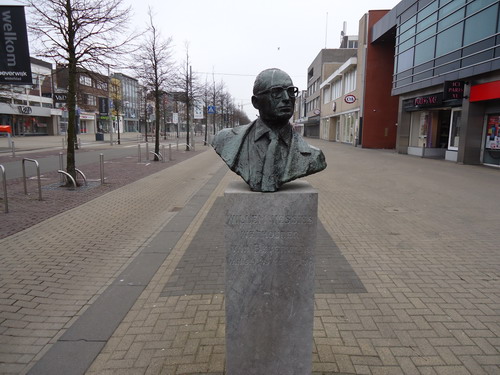 Vessies
De voormalige melkboer Willem Vessies was lange tijd actief in de Beverwijkse gemeentepolitiek. Als wethouder ontwikkelde hij samen met zijn collega bestuurders het concept van Beverwijk als ‘city’. Die allures heeft Beverwijk nooit waar kunnen maken. De waardering voor Willem Vessies was er niet minder om. Hij stond bekend als een hulpvaardig en aimabel mens. Bovendien streed hij voor het behoud van de Breestraat als warm kloppend hart van de stad. De Beverwijkse middenstand liep dan ook met hem weg. In 1984 overleed hij. Kunstenaar Gerard van der Leeden kreeg de opdracht voor een borstbeeld van deze stadsbestuurder. Van der Leeden ging grondig te werk. Hij selecteerde foto’s van de overledene en sprak met allerlei mensen die Vessies hadden gekend. Het is een levendig hoofd geworden dat zelfbewust de wereld aanschouwt. Schuin van ons wegkijkend in een bevroren momentopname. Dat maakt dat deze kop het gewone borstbeeld ontstijgt.       

Bron: Blik op Beeld, Tekstbureau Zonneveld & Thöne i.o.v. gemeente Beverwijk, 2006.
Foto en bewerking: Co Backer

Keywords: bwijk Openbare Kunstwerken