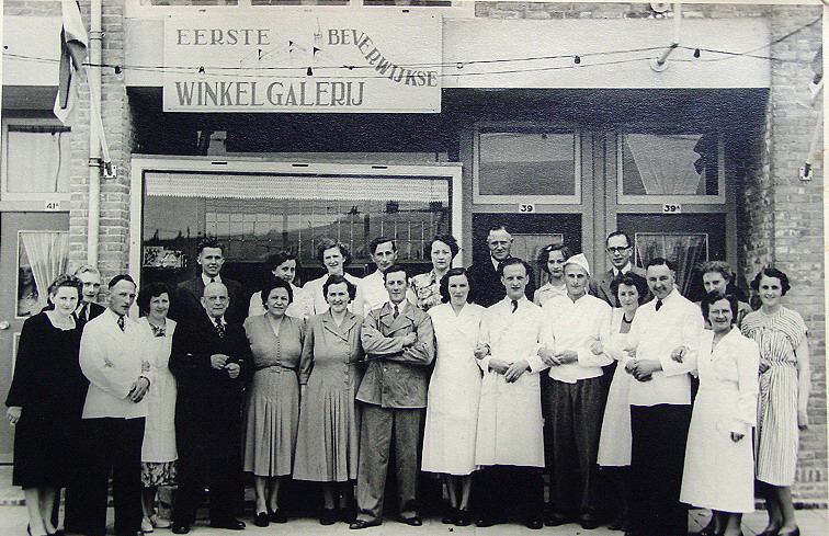 Winkelgalerij Hendrik Mandeweg
Winkelgalerij Hendrik Mandeweg. Van links naar rechts: kapper Brouwer met vrouw, kaasboer Niesten met vrouw,  fietsenmaker Walgien met vrouw, groenteboer Weel met vrouw. Daarachter:  Vivo kruidenier Vonk met vrouw, daarnaast: loodgieter Van der Wal met vrouw en dochter en zoon, Daarvoor: slager Kamer met vrouw, bakker Schoone met vrouw, Visboer Van Veelen met vrouw,  daarachter twee vrouwen(?) naast mevrouw Vonk links twee personen(?)kinderen van(?).

Foto:  Maarten van Veelen
Keywords: bwijk Hendrik Mandeweg